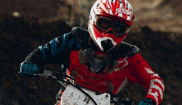 Person with helmet and goggles on riding a dirt bike.