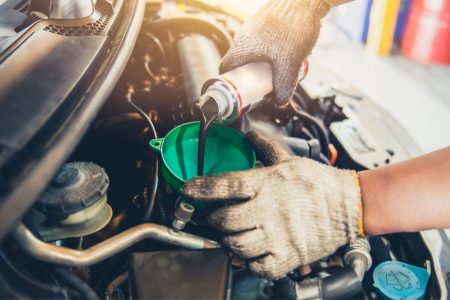 Man pouring engine assembly lube into a car.