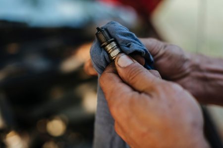 Person wiping off a spark plug with a cloth.