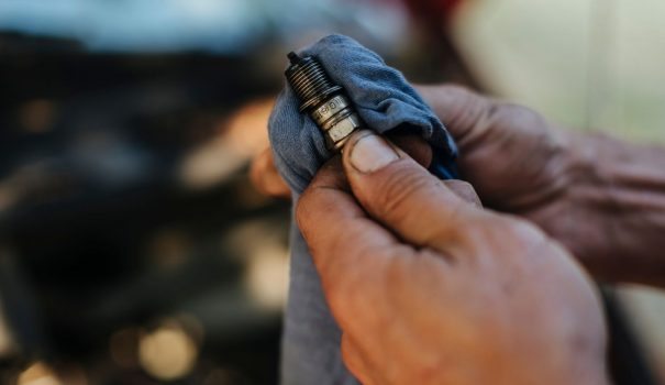 Person wiping off a spark plug with a cloth.