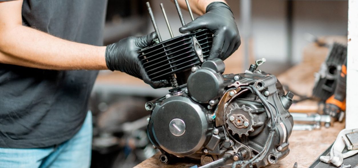 Person working on a motorcycle engine.