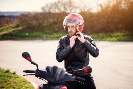 Man putting on helmet to ride a motorcycle.
