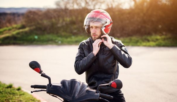 Man putting on helmet to ride a motorcycle.