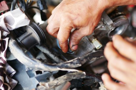 Man's hands working on a motorcycle engine.