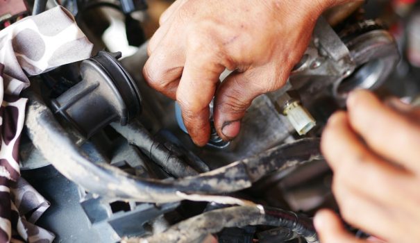 Man's hands working on a motorcycle engine.