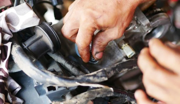 Man's hands working on a motorcycle engine.