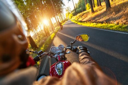 Person riding a motorcycle down a two lane road.