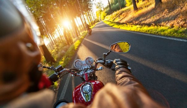 Person riding a motorcycle down a two lane road.